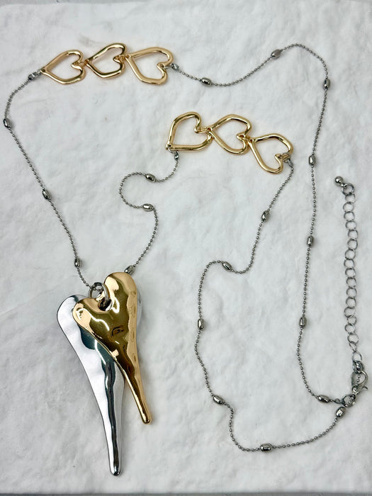 Necklace with gold and silver heart-shaped pendants on a light gray background