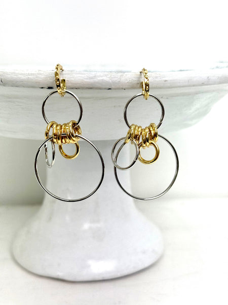 Gold and silver hoop earrings on a white stand