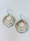 This image displays the Victoria Earrings, characterized by their elegant circular design. The earrings feature multiple loops in a combination of silver and gold colors, creating a sophisticated and layered visual effect.