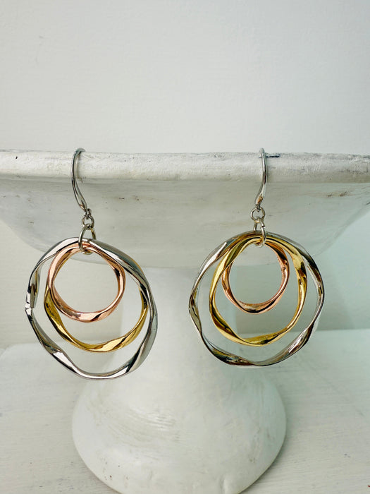 Pair of gold and silver hoop earrings on a white surface