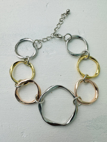 An elegant bracelet with a mix of silver, gold, and rose gold open circles linked together.