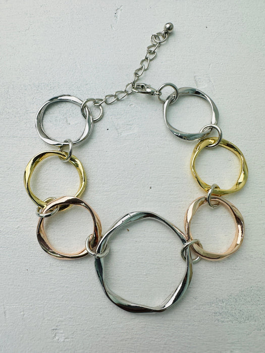An elegant bracelet with a mix of silver, gold, and rose gold open circles linked together.