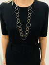A person wearing a black dress with a Victoria necklace consisting of open circles in silver, gold, and rose gold tones.