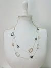 A multilayered necklace with silver-colored chains and clear, black, and pink square beads displayed on a mannequin bust