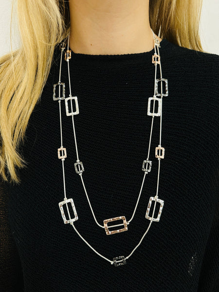 Long necklace with square pendants on a black sweater