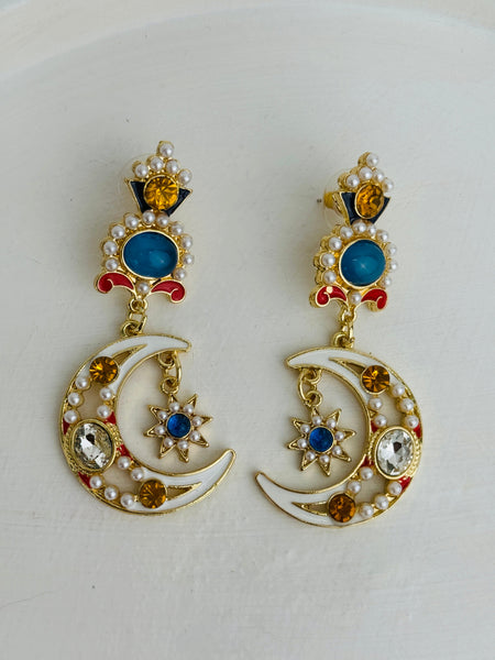 Pair of decorative earrings with moon and star design on a white background