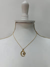 Gold necklace with a moon and star pendant displayed on a mannequin bust