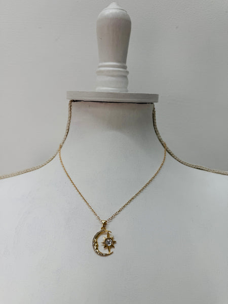 Gold necklace with a moon and star pendant displayed on a mannequin bust