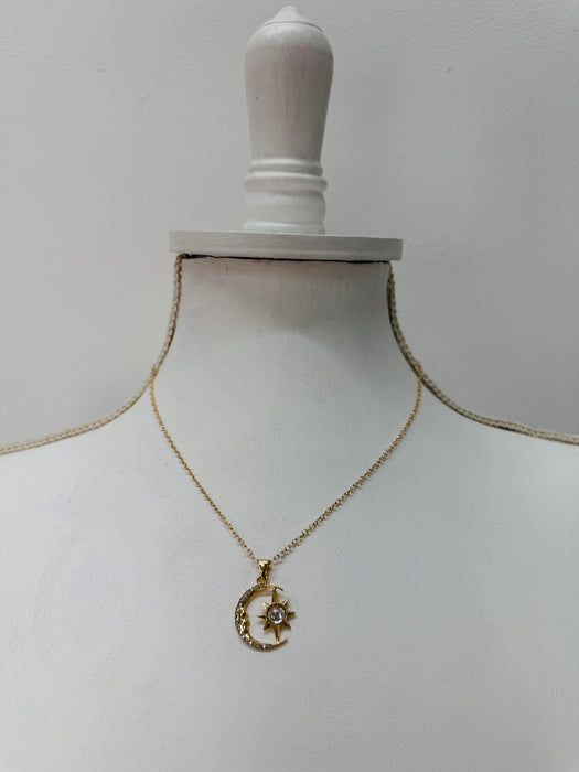 Gold necklace with a moon and star pendant displayed on a mannequin bust
