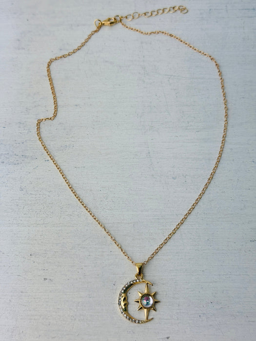 Gold necklace with a moon and star pendant on a light gray background