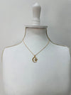 Gold necklace with a pendant on a mannequin bust against a plain background