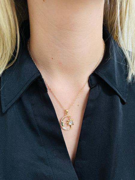 Necklace with a moon and star pendant worn by a person in a black shirt.