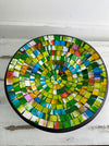 Top view of handmade mosaic glass bowl in citrus tones showing circular yellow, green and orange glass pattern.