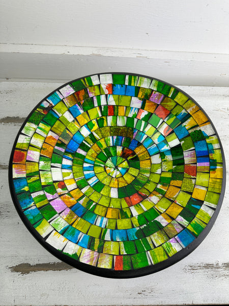 Top view of handmade mosaic glass bowl in citrus tones showing circular yellow, green and orange glass pattern.