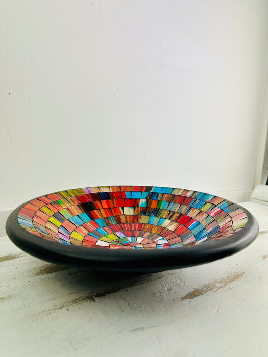 Angled view of handmade Fragaria mosaic bowl on white surface showing bright red and pink tones in glass pattern.