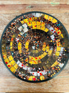 Top view of handmade mosaic glass bowl in Siena tones showing circular pattern of amber, gold, and copper mosaic pieces.