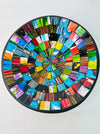 Top view of handmade mosaic bowl with red, blue, green, and gold glass pieces arranged in circular pattern.