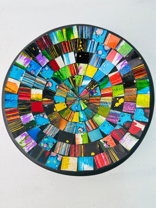Top view of handmade mosaic bowl with red, blue, green, and gold glass pieces arranged in circular pattern.