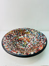 Top view of multicoloured handmade mosaic bowl showing detailed glass pattern with black rim on white background.