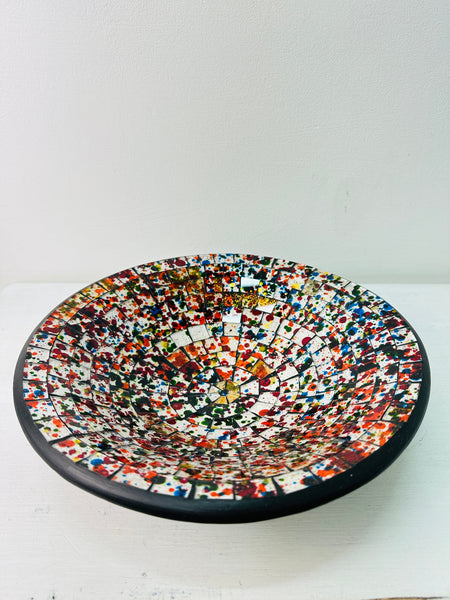 Top view of multicoloured handmade mosaic bowl showing detailed glass pattern with black rim on white background.