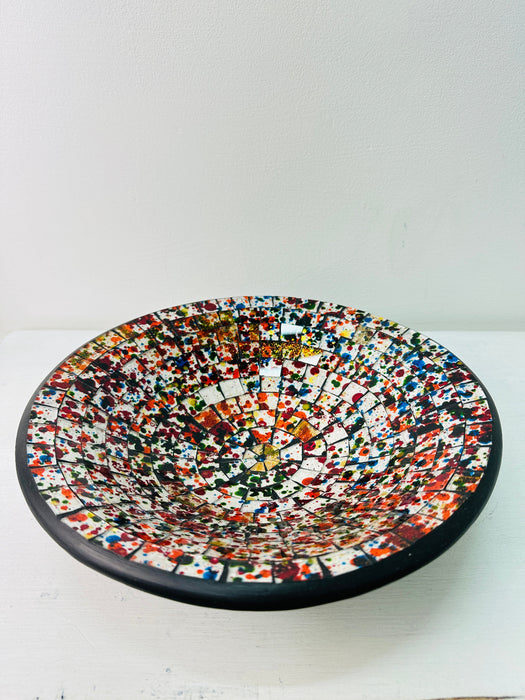Top view of multicoloured handmade mosaic bowl showing detailed glass pattern with black rim on white background.