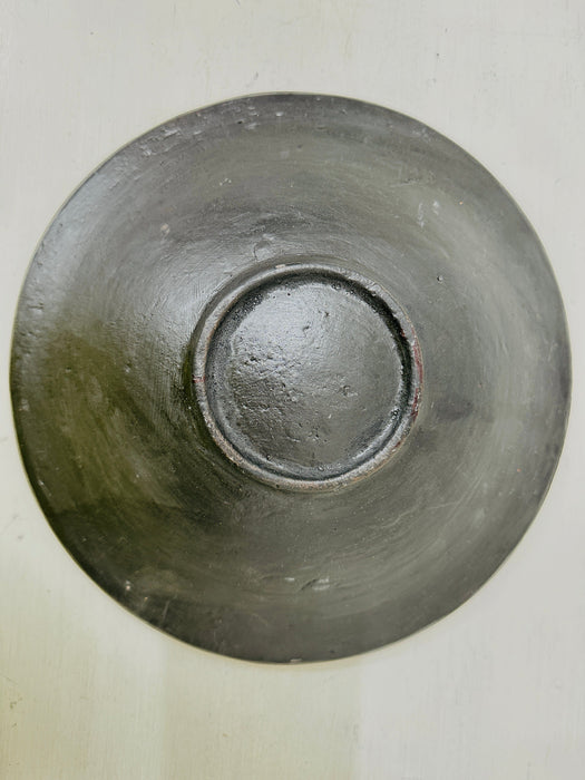 Underside of mosaic bowl showing smooth terracotta base and circular form