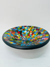 Handmade mosaic glass bowl in bright Sterope colours, showing curved terracotta base and reflective glass surface.