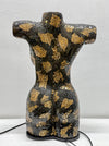 A decorative ceramic torso sculpture with a glossy black and gold mosaic crackle pattern, displayed against a light gray wall.