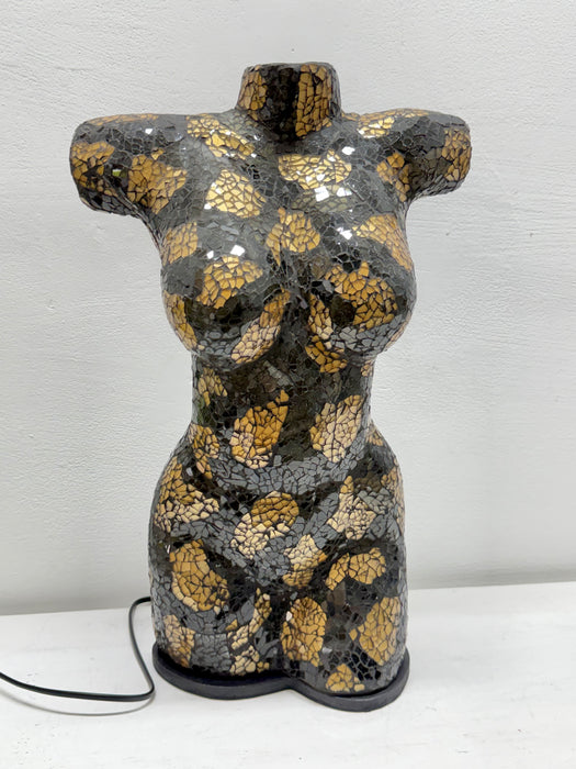 A decorative ceramic torso sculpture with a glossy black and gold mosaic crackle glaze, displayed on a white surface against a white wall.