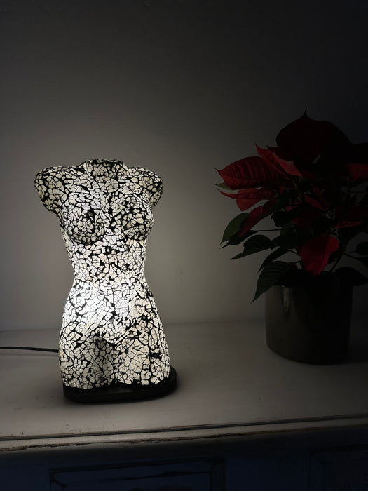 Silver mosaic torso lamp creating ambient glow on a table