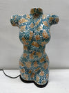 A female torso sculpture with a mosaic pattern in teal blue, gold, and white, standing on a black base with a power cord visible.