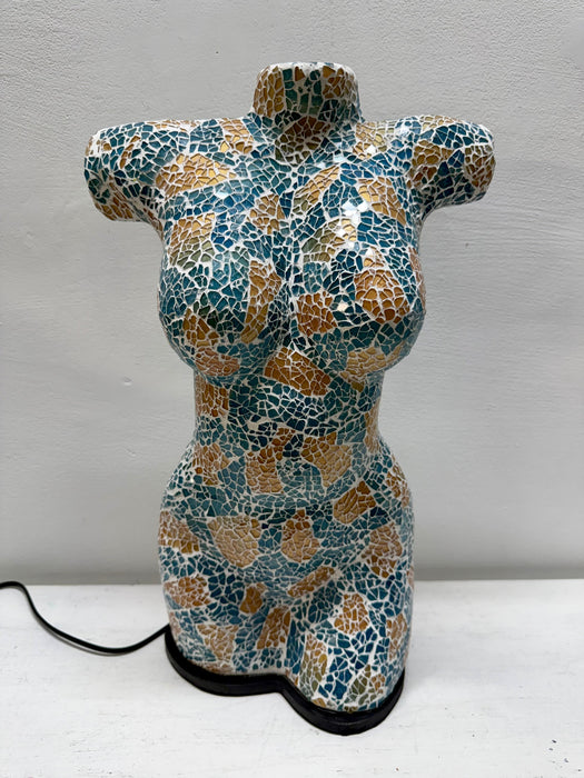 A female torso sculpture with a mosaic pattern in teal blue, gold, and white, standing on a black base with a power cord visible.