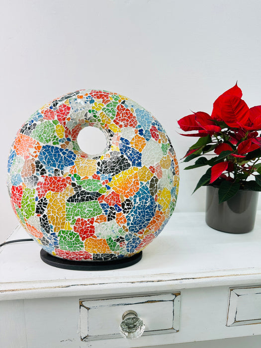 Mosaic Donut Lamp Medium – Crackle Multi displayed on white table beside red poinsettia, showing handmade colourful mosaic glass design