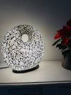 Silver mosaic donut lamp glowing in low light setting