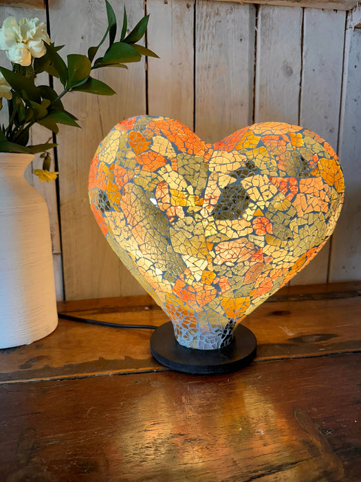 Heart-shaped mosaic lamp glowing warmly with rainbow glass pieces.