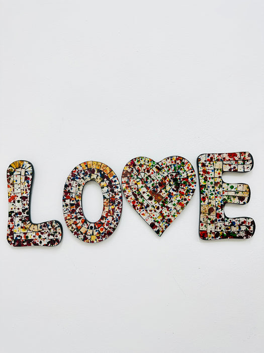 A mosaic wall piece with the word 'LOVE' broken down into individual letters, each painted in a spectrum of colors.