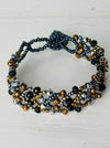 Multistrand beaded bracelet with black, gold, and silver beads on a white background