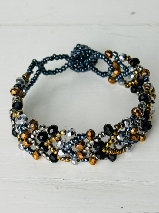 Multistrand beaded bracelet with black, gold, and silver beads on a white background