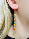 Close-up of colorful flower earrings being worn.