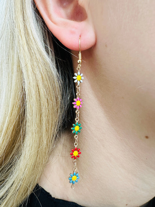 Close-up of colorful flower earrings being worn.