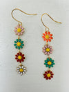 A pair of earrings with multiple colorful floral designs on a gold-colored hook.