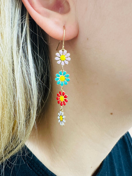 Colorful flower-shaped earrings worn by a person with blonde hair.