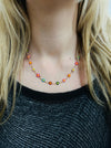 delicate necklace with small multicolour enamel flower charms on a fine chain on a model