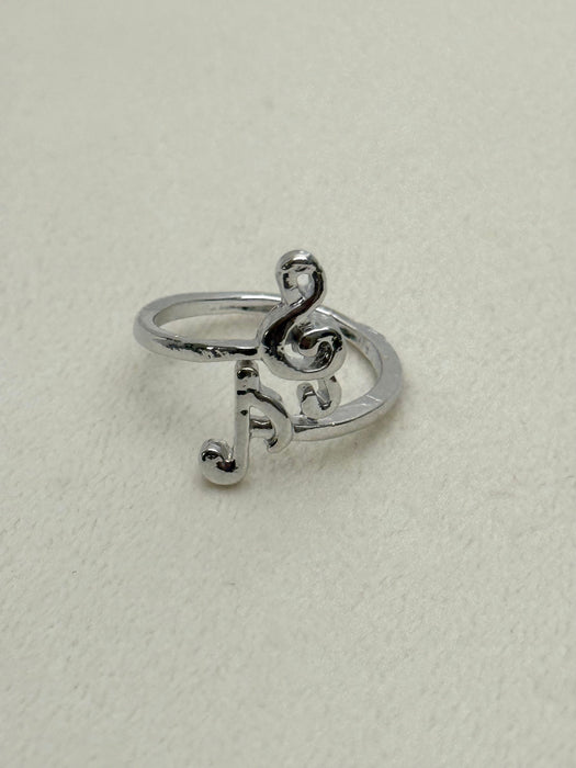 Silver ring with musical note design on a light gray background
