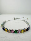 An adjustable bracelet with a silver metal bar and multicolored rainbow crystal details.