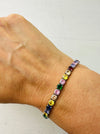 Multicolored gemstone bracelet on a wrist against a white background