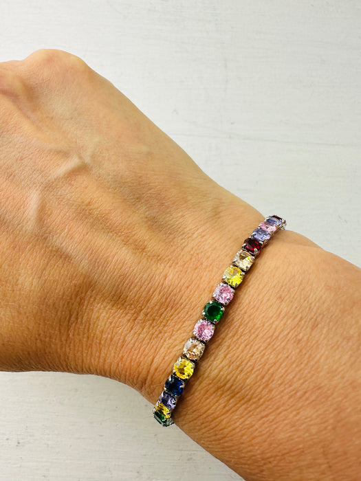 Multicolored gemstone bracelet on a wrist against a white background