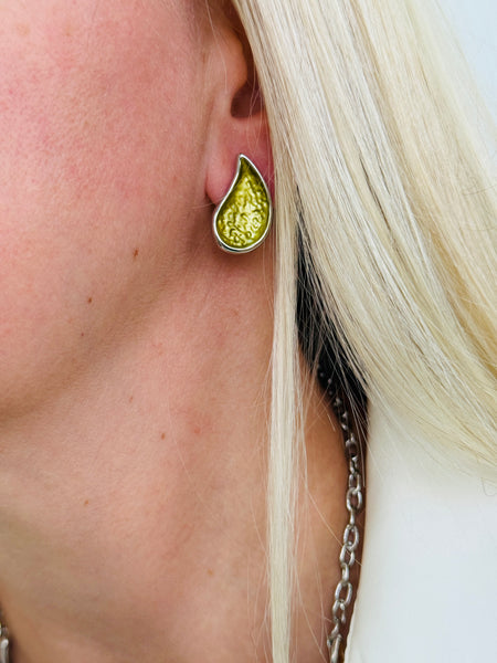 Olive green teardrop enamel stud earrings with silver tone, displayed on a model.