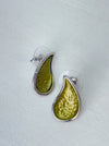 Olive green teardrop enamel stud earrings with silver tone, displayed on a white table.