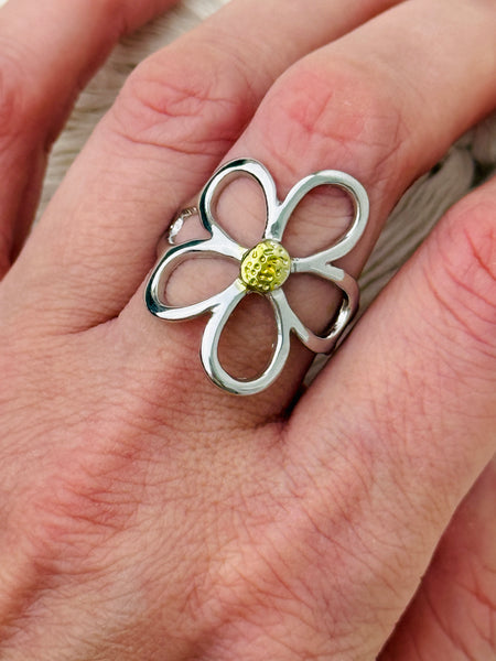 Simple silver open petal flower ring with gold centre, displayed on a model.